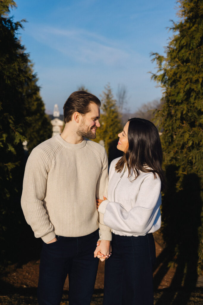 Couple walking together on tree lined path during sunrise engagement session