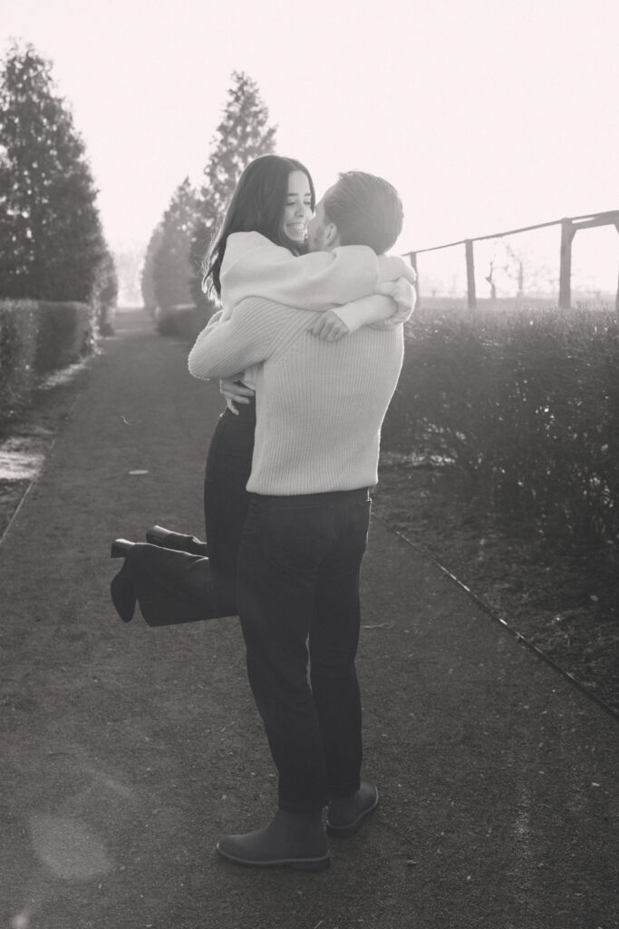 Black and white photo of couple lifting and hugging during engagement session