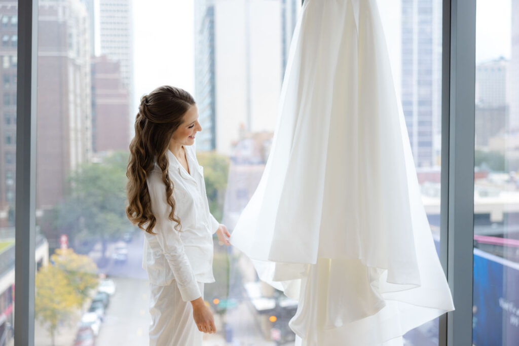 Bride looking out hotel window beside her wedding dress at The Viceroy Chicago