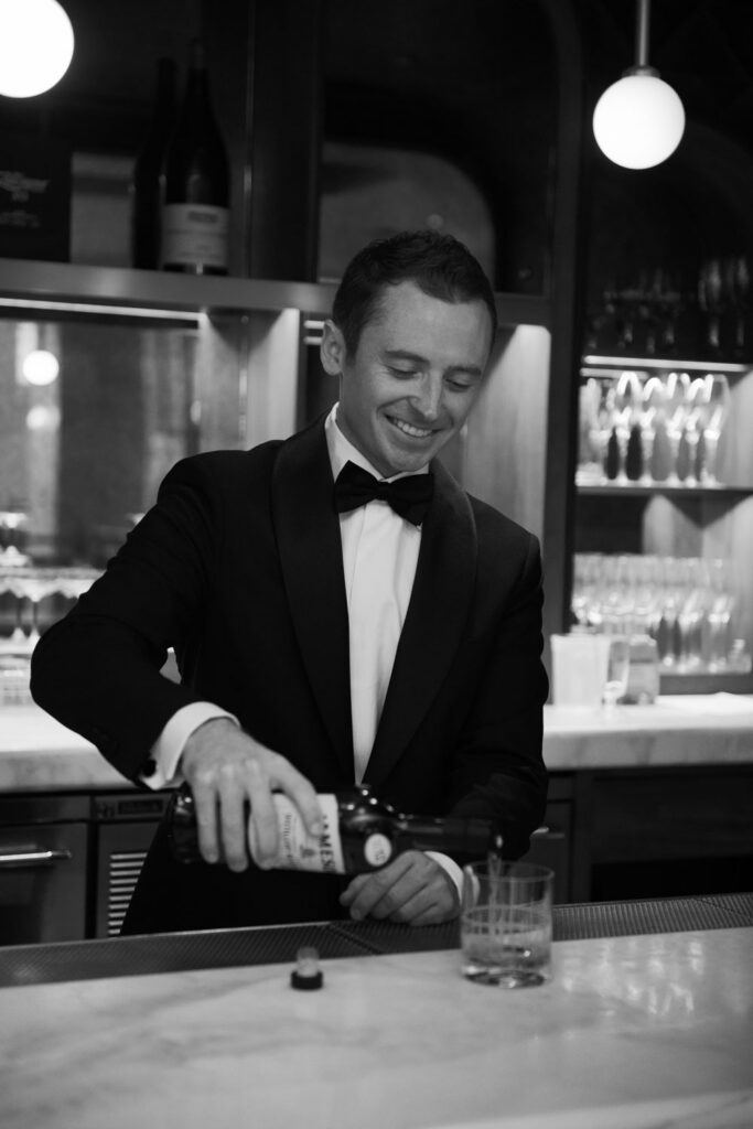 Groom pouring a drink at the bar while getting ready