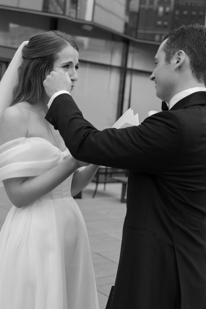 Groom gently wiping away a tear from the bride’s face during their first look