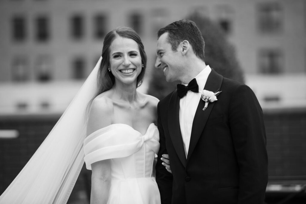 Black and white portrait of bride and groom smiling together outdoors