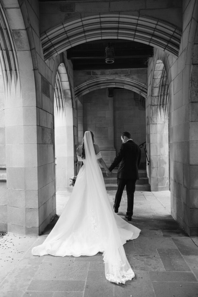 Bride and groom walking together through arched stone corridor at Fourth Presbyterian Church in Chicago