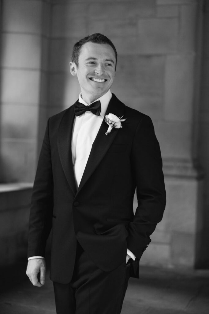 Groom portrait in tuxedo beside stone architecture