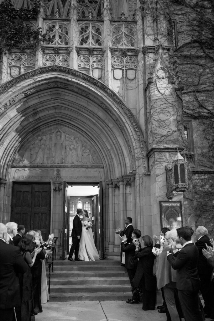 Bride and groom kissing outside the church as guests cheer