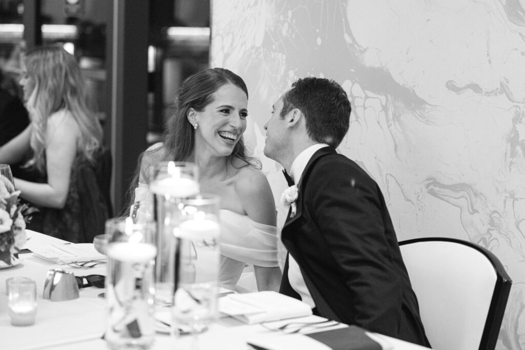 Bride and groom sharing a kiss at their reception table