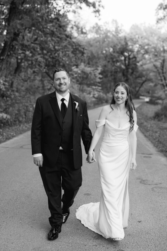 Bride and groom walking together along a tree lined path at The Morton Arboretum