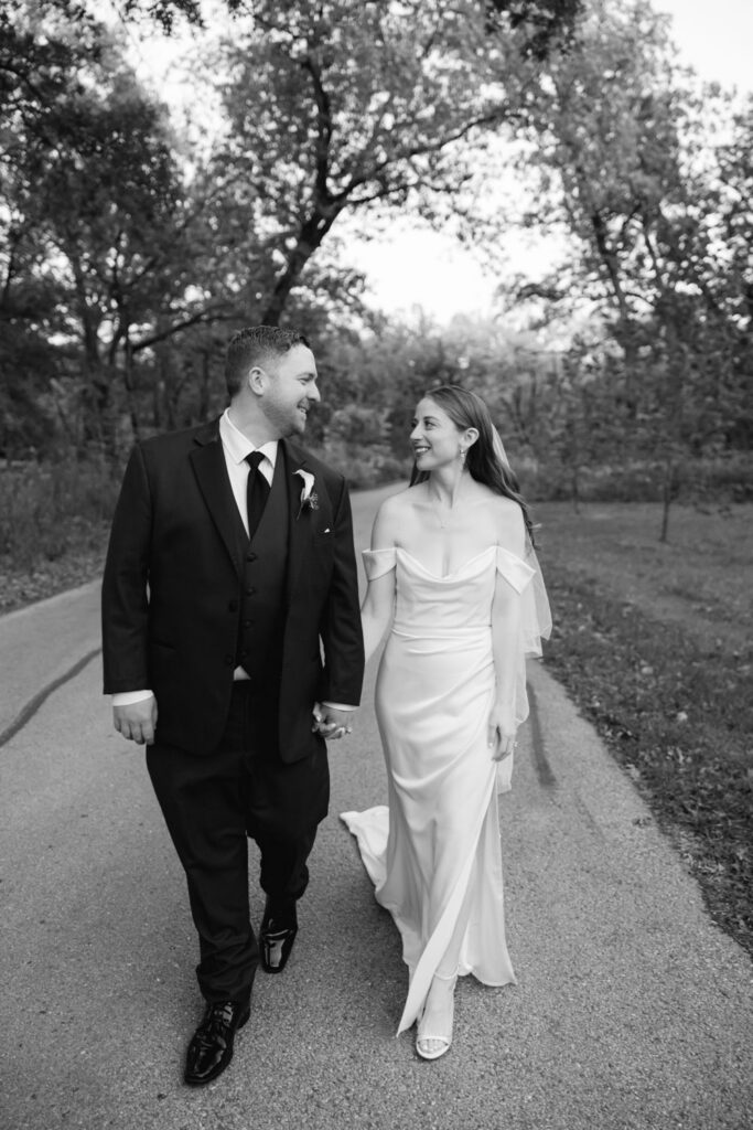 Bride and groom smiling while walking together during Arboretum wedding portraits
