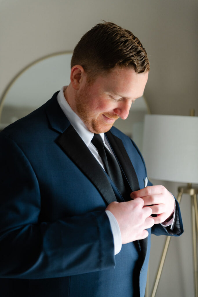 Groom adjusting suit jacket while getting ready for wedding