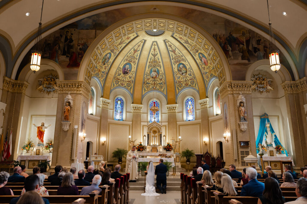 Catholic wedding ceremony inside church with guests seated in pews