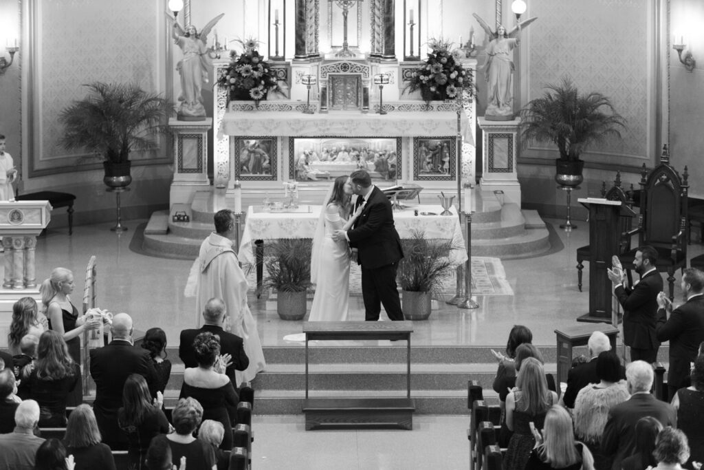 Bride and groom sharing first kiss during church wedding ceremony