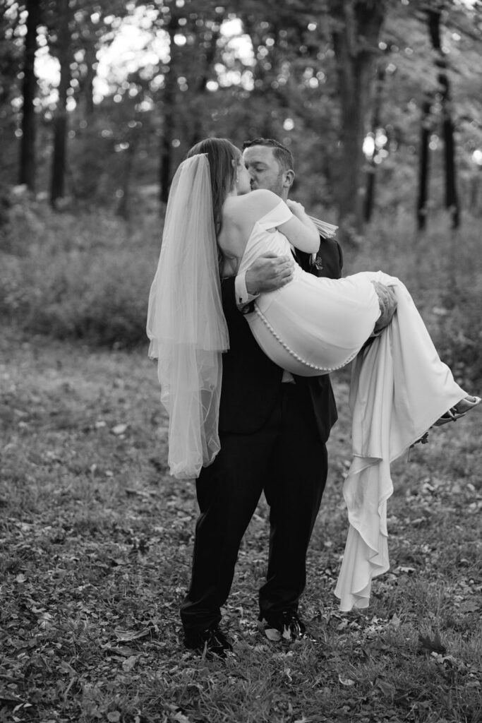 Groom lifting bride during playful wedding portrait