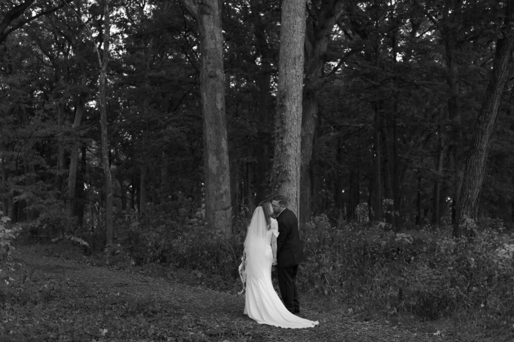 Bride and groom walking down tree lined road at Morton Arboretum