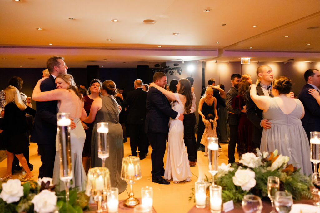 Bride and groom dancing together on packed dance floor