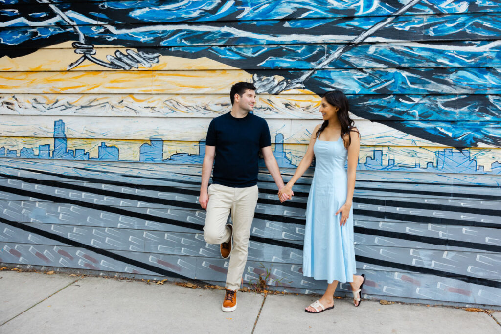 Couple walking hand in hand past blue mural in Pilsen neighborhood