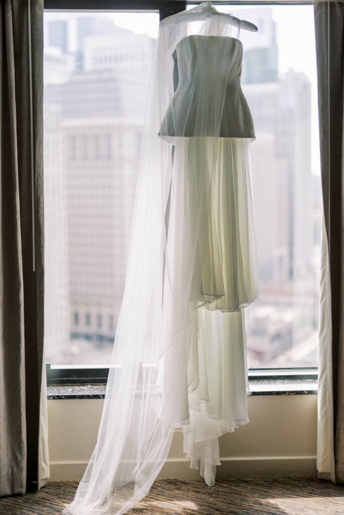 Bride’s Alexandra Grecco wedding gown hanging in a Chicago hotel window before the ceremony.