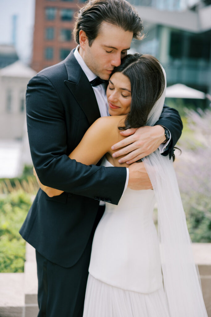 Couple embracing with downtown Chicago skyline in the background on their wedding day.