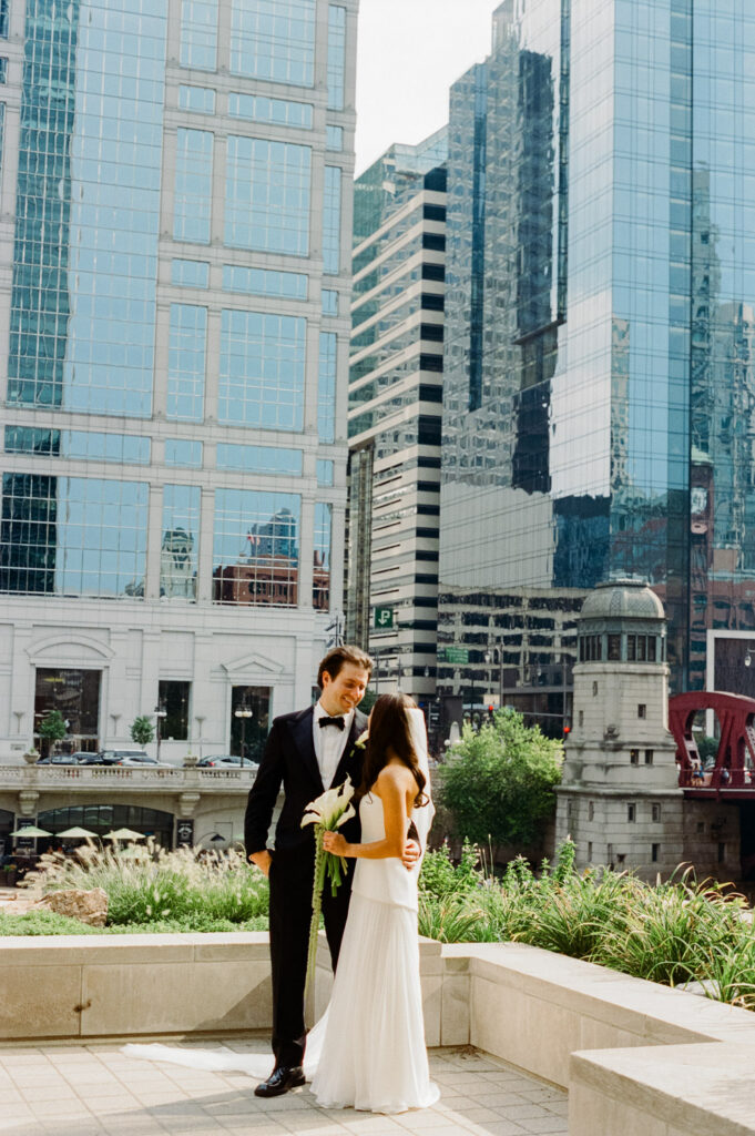 Couple embracing with downtown Chicago skyline in the background on their wedding day.