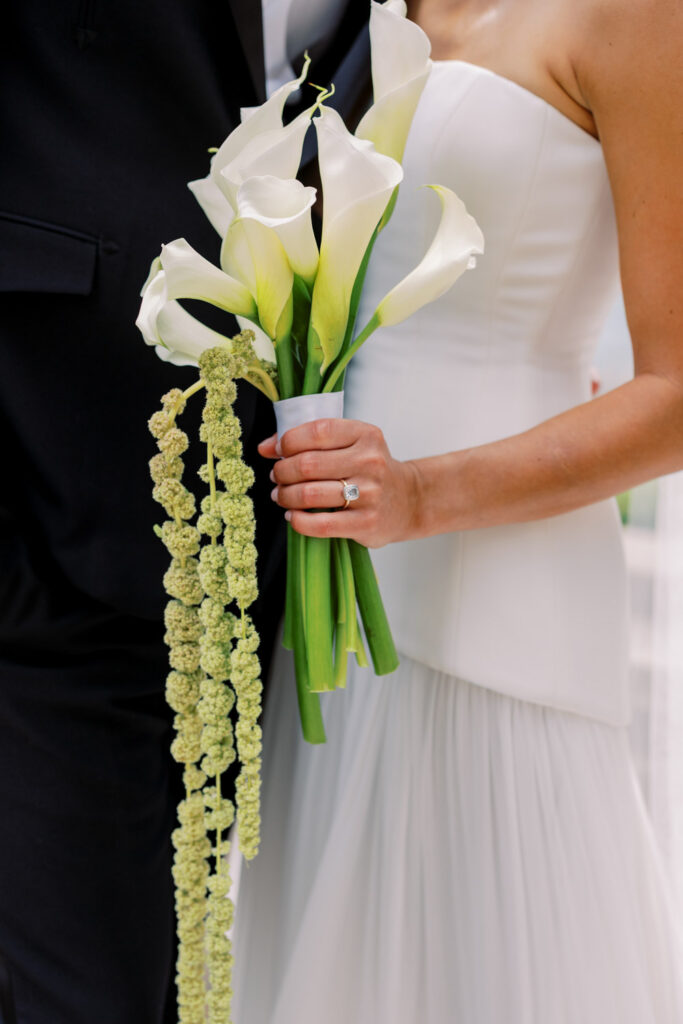 Close up of bride holding cascading calla lily bouquet by Fleur during summer Chicago wedding portraits.