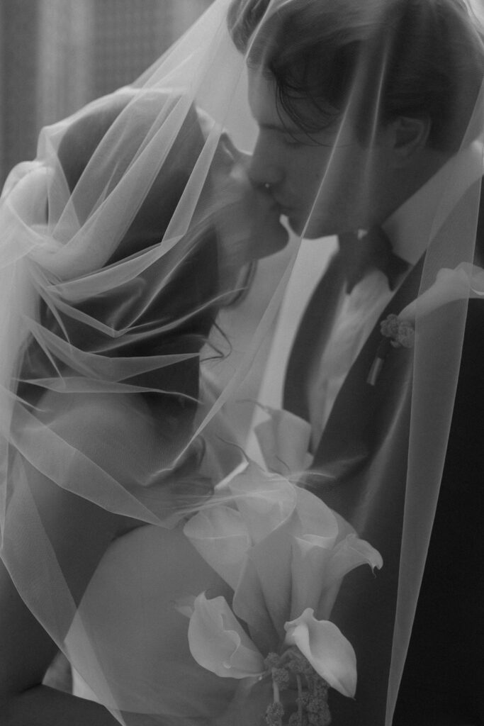 Bride and groom wrapped in veil fabric during riverfront wedding portraits in Chicago.