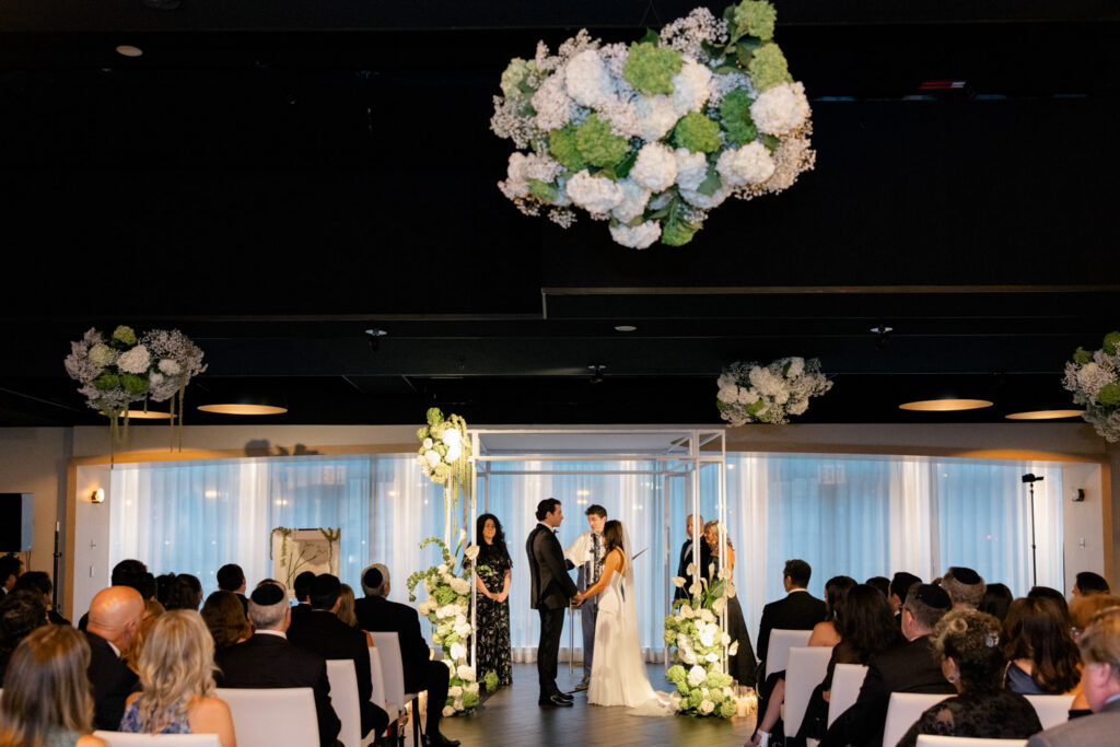 Bride and groom standing beneath a floral chuppah during Jewish wedding at RPM Events Chicago.