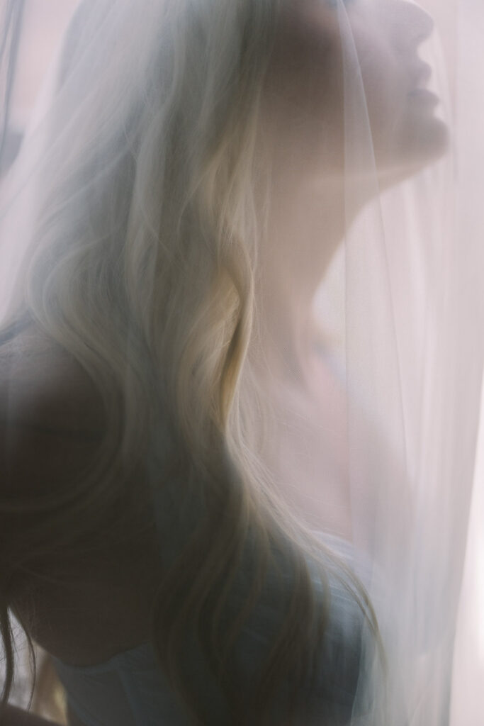 Soft focus portrait of bride through veil in natural light