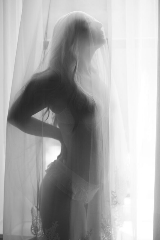 Soft bridal boudoir silhouettes with wedding veil in natural window light