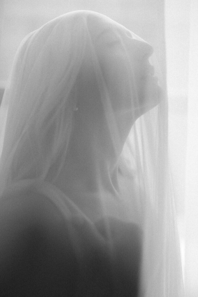 Soft bridal boudoir silhouettes with wedding veil in natural window light