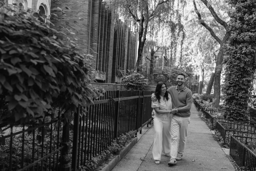 Couple walking together on tree lined Lincoln Park street in Chicago black and white engagement photo