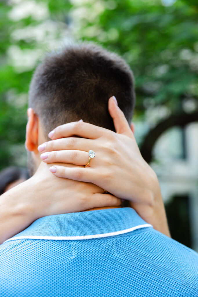 Close up of engagement ring with hand resting on partner’s neck natural light detail photo