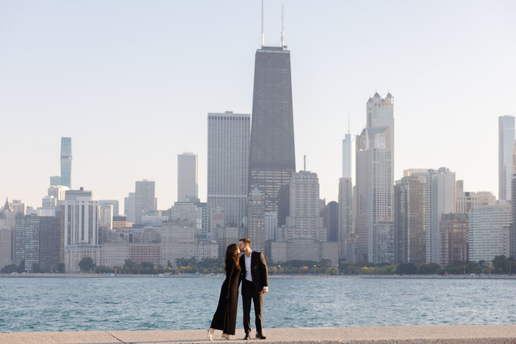Couple standing by Lake Michigan with Chicago skyline in background engagement session