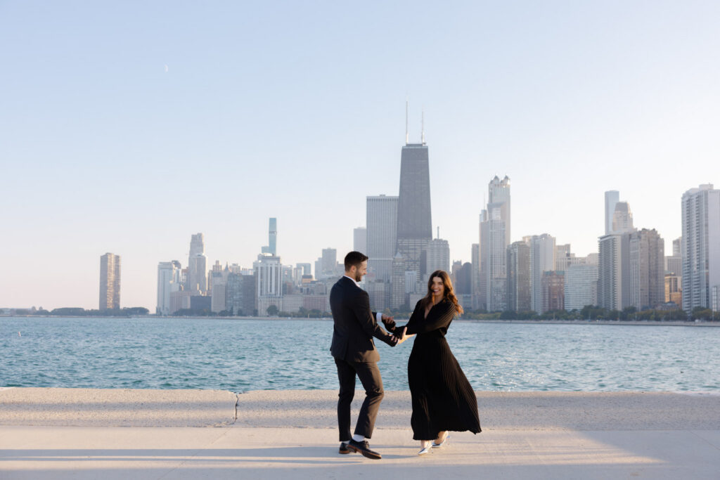 Couple walking together along Chicago lakefront with skyline view Lincoln Park engagement session
