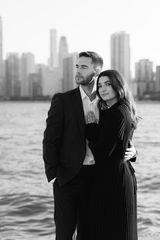 Couple standing together by water with Chicago skyline behind them engagement session