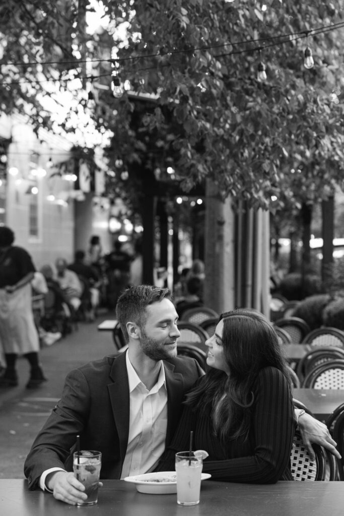 Couple sitting at outdoor restaurant table with drinks in Lincoln Park Chicago engagement session