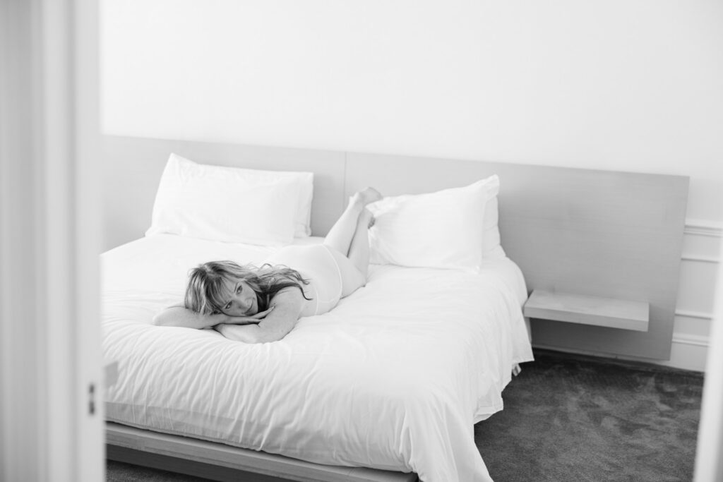 Overhead view of woman laying on bed in bright, minimal room
