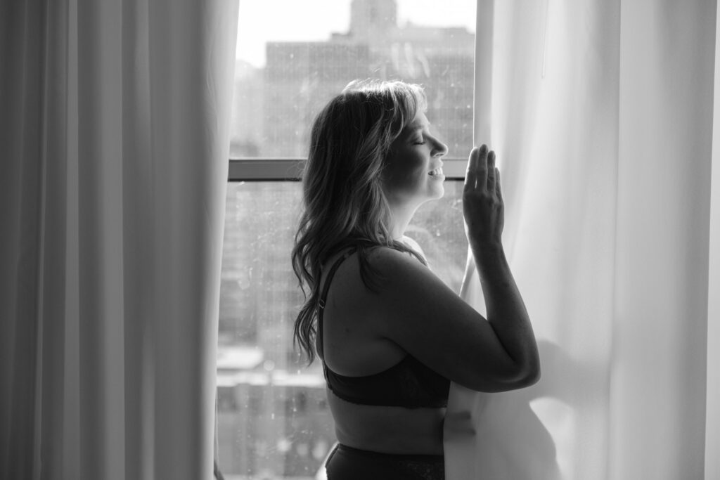 Black and white portrait of woman standing by window looking outside