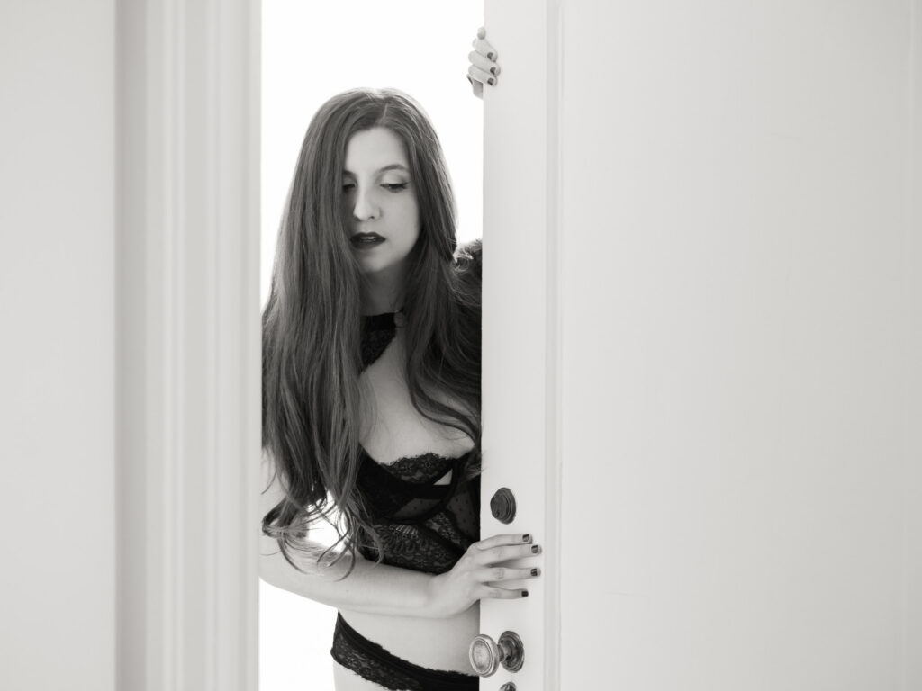 Chicago boudoir portrait of woman in black lace lingerie peeking through doorway
