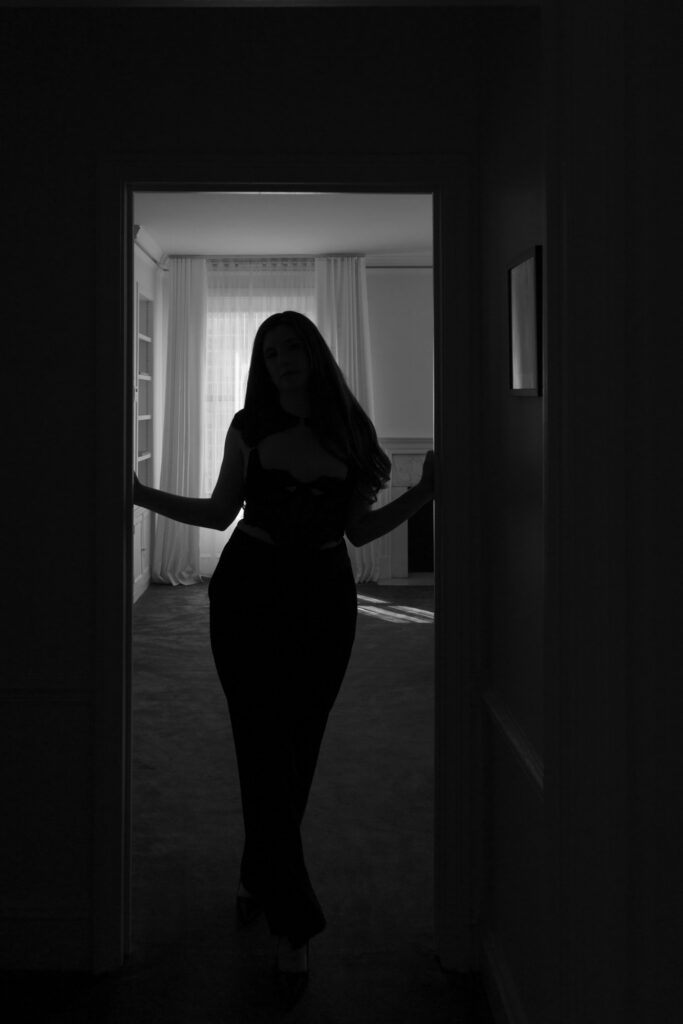 Moody black and white boudoir silhouette of woman standing in hotel doorway