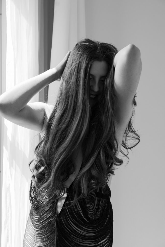 Black and white boudoir portrait of woman in fringe dress by window