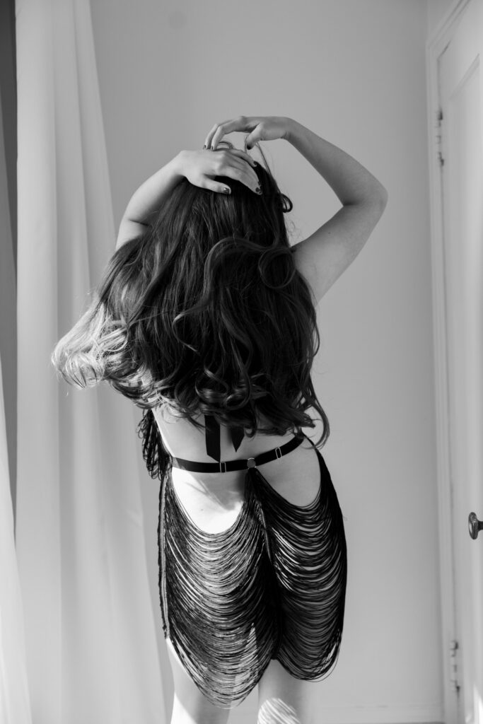 Black and white boudoir photo of woman from behind in black fringe dress