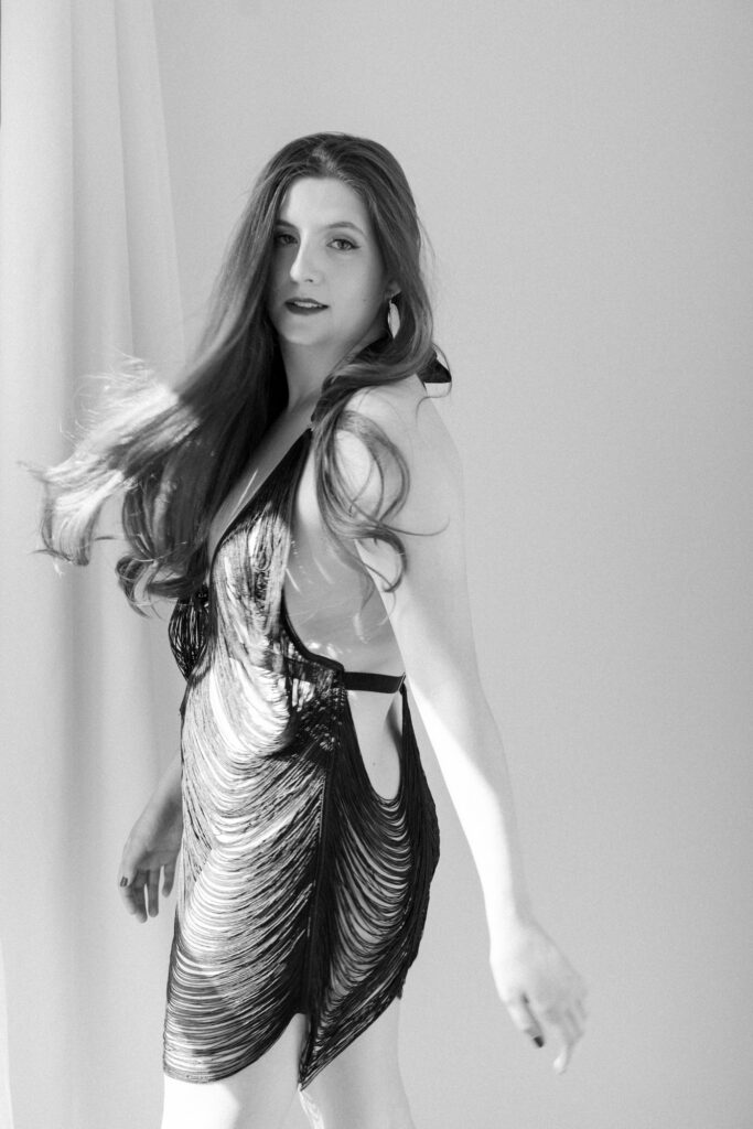 Black and white boudoir photo of woman turning in black fringe slip