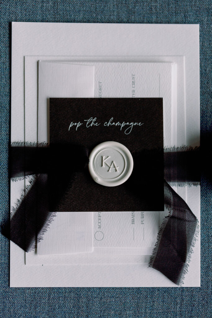 Wedding invitation suite with black and white design details photographed on a textured surface.