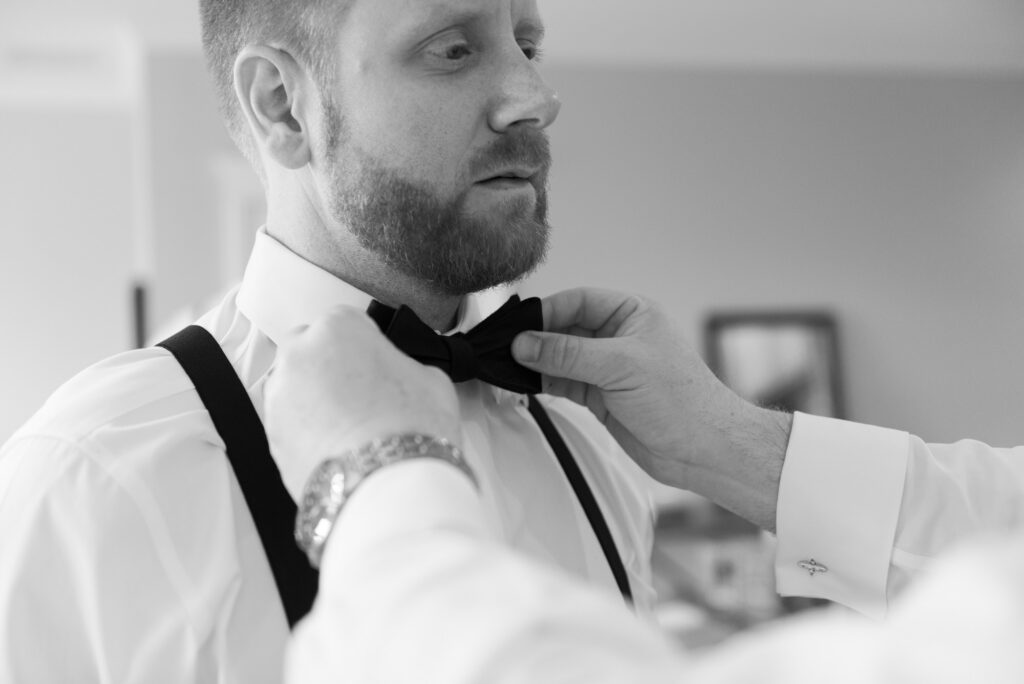 Groom adjusting his bow tie while getting ready for his wedding day in Chicago.