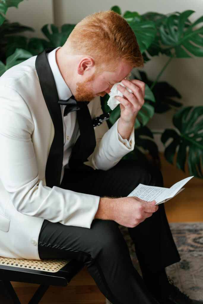 Groom sitting and reading a note before the first look.