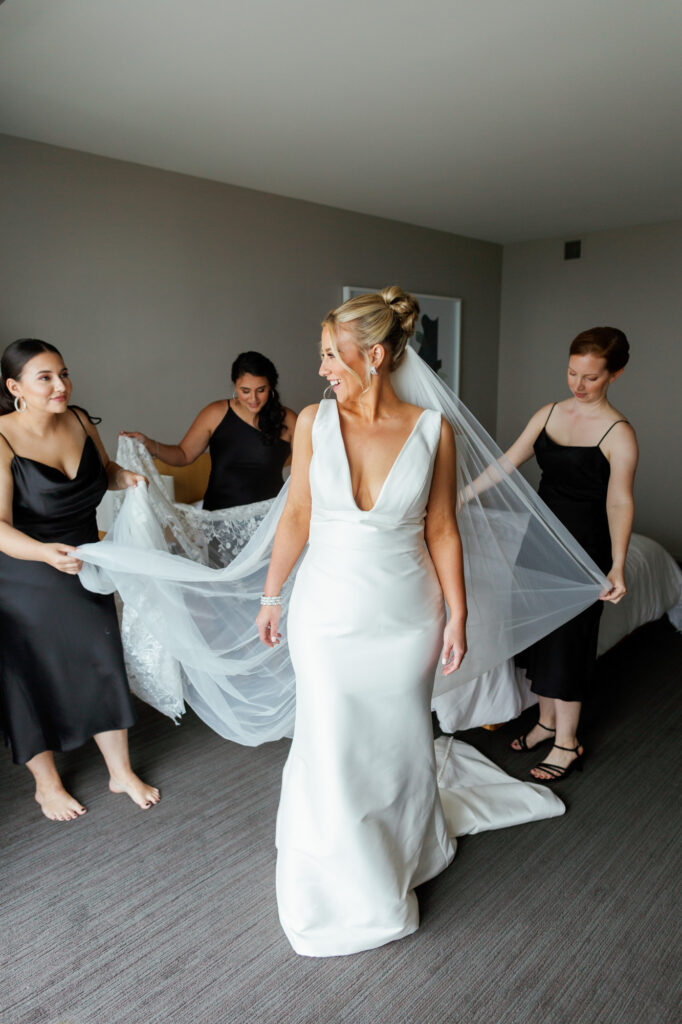Bride getting ready with her bridesmaids helping her into her dress in a Chicago hotel suite.