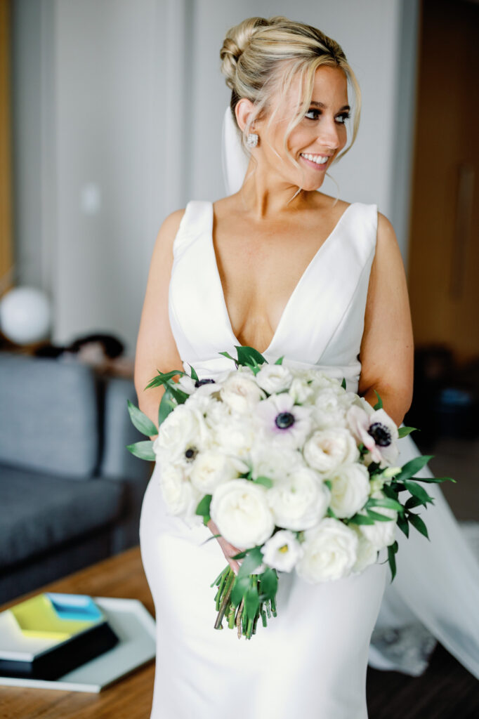 Bride holding her bouquet and smiling in her wedding dress before the ceremony.