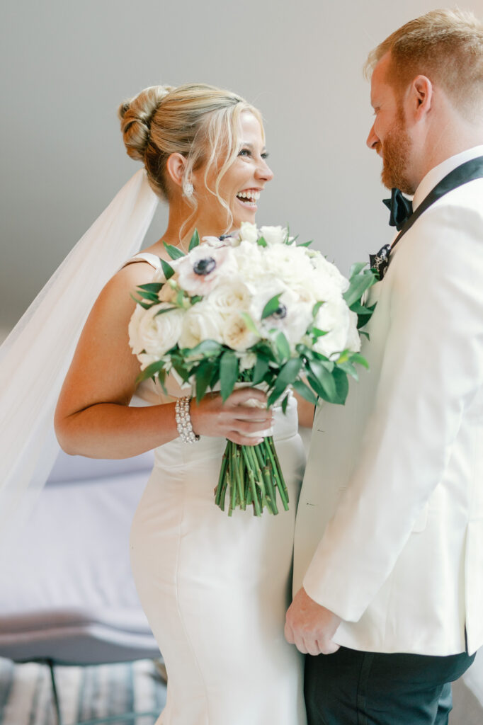 Bride and groom laughing together immediately after their first look moment.