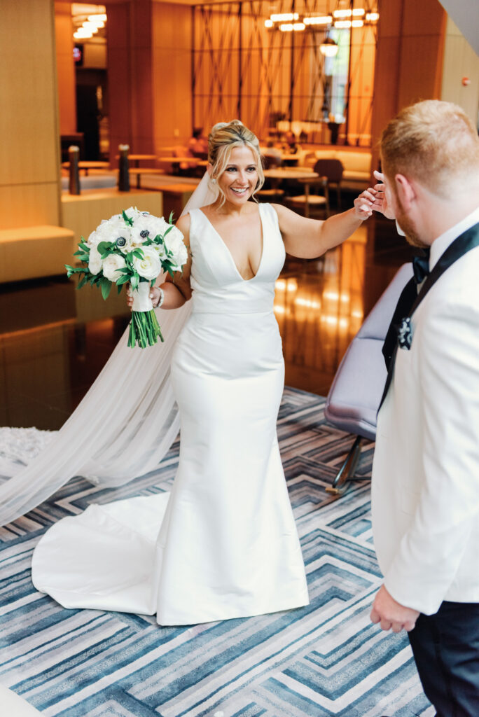 Bride and groom embracing during their first look in a quiet hotel lobby.