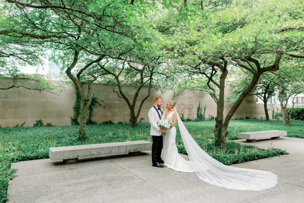 Bride and groom embracing beneath the trees in the Art Institute of Chicago Gardens during wedding portraits.