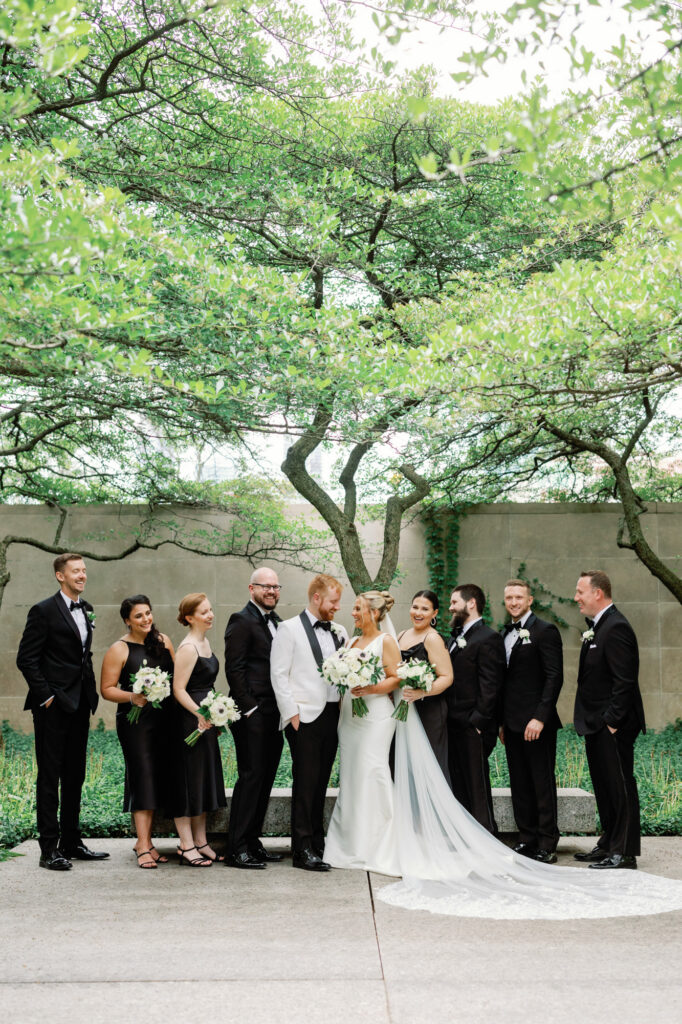 Full wedding party standing together in the Art Institute of Chicago Gardens for formal portraits.